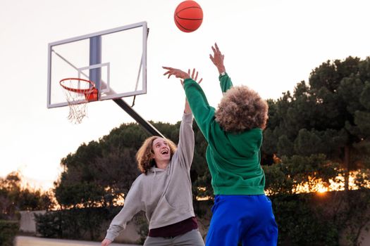 couple of young friends playing basketball outdoors on a city court, concept of urban sport in the street