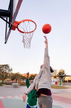 two young friends play basketball on a city court, concept of urban sport in the street