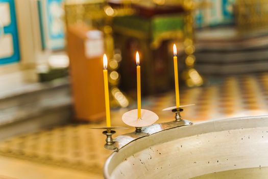 Font and 3 burning candles with water for baby in church for Epiphany. Prepearing for bathing for child in a baptistery