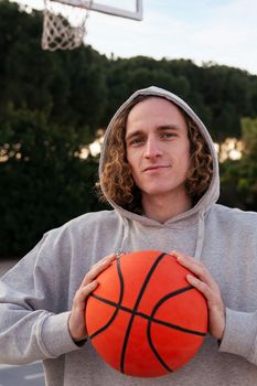 young caucasian man holding a basketball in his hands, concept of urban sport outdoors, copy space for text