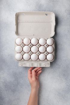 White eggs in a large paper container box top view on a neutral background