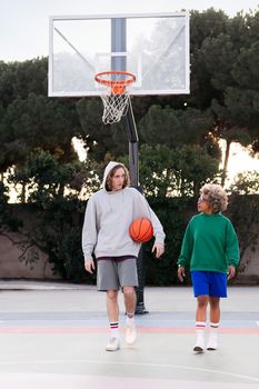 latin woman and caucasian man chatting walking down the court after basketball practice, concept of friendship and urban sport in the street, copy space for text