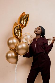 Eid al-Adha celebration. Muslim national holiday. Attractive girl with golden helium balloons isolated peach background