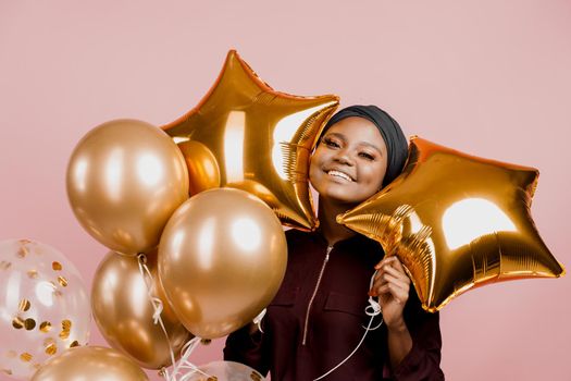 Muslim new year party with golden balloons for black woman. African attractive girl celebration of the end of year. Happy emotion