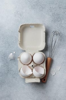 White eggs in a small paper container box top view on a neutral background