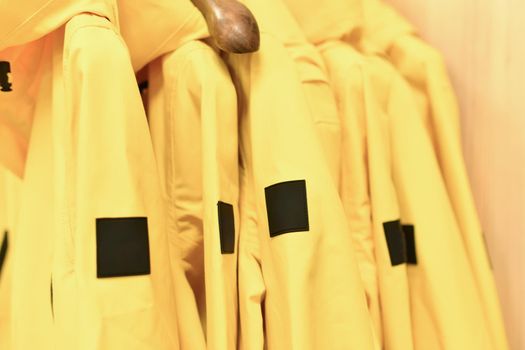A row of yellow jackets on a hanger in a shop