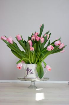 Fresh pink tulip flowers bouquet on shelf in front of stone wall. View with copy space.