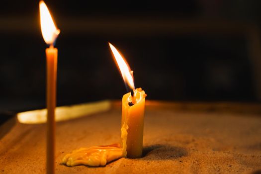 Burning candles close-up on dark background in church. Tragedy. Orthodox tradition and faith. Equipment for praying. Pray for people life. Pray to god