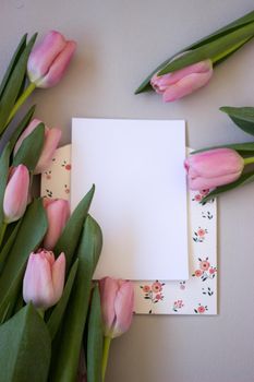 Pink tulips on wooden background. Open book, craft gift box and coffee. Mothers Day, Women Day, floral desing, blogger table and spring concept, copy space, top view.