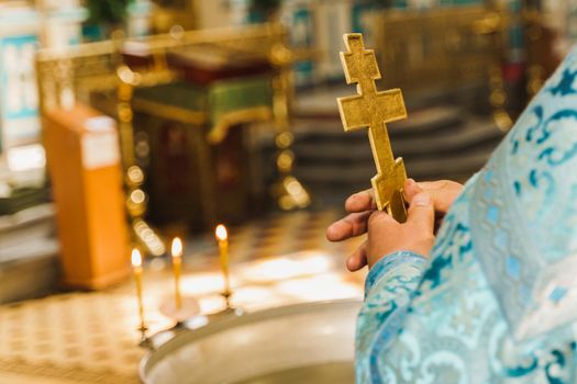 Holy father near babtistery in his robe with a golden cross in his hands in church. Orthodox tradition and faith. Equipment for praying