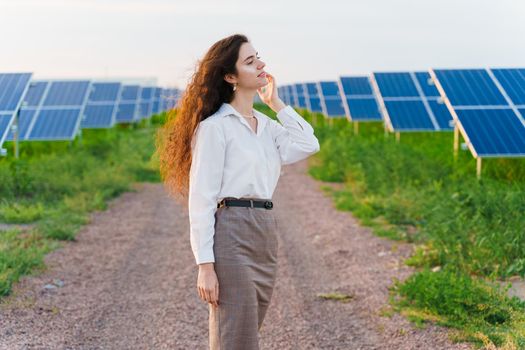 Girl stand between 2 Solar panels row on the ground at sunset. Free electricity for home. Sustainability of planet