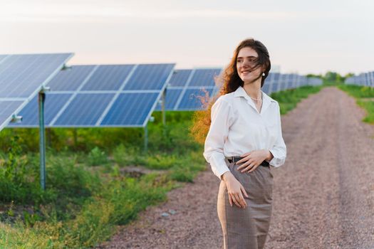 Girl stand between 2 Solar panels row on the ground at sunset. Free electricity for home. Sustainability of planet