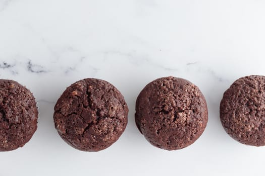 The row of chocolate muffins on a white marble table