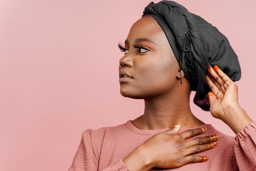 Muslim woman with closed eyes close-up. Relax and meditation. African black attractive girl portrait isolated on pink background