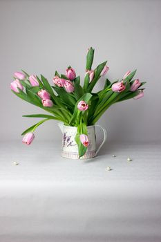 Fresh pink tulip flowers bouquet on shelf in front of stone wall. View with copy space.