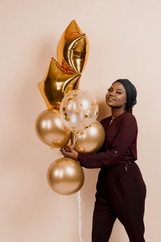 Muslim new year party with golden balloons for black woman. African attractive girl celebration of the end of year. Happy emotion