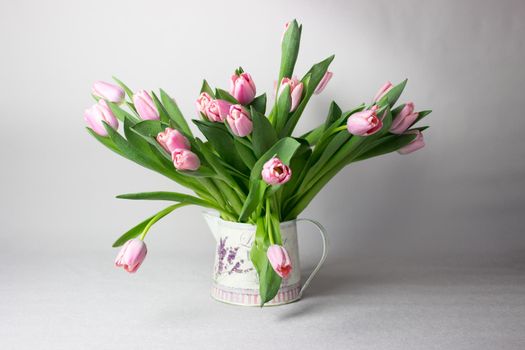 Fresh pink tulip flowers bouquet on shelf in front of stone wall. View with copy space.