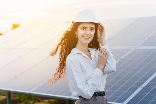 Engineer with solar panels stands in row on the ground at sunset. Green energy. Solar cells power plant business