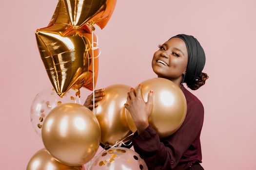 Muslim new year party with golden balloons for black woman. African attractive girl celebration of the end of year. Happy emotion