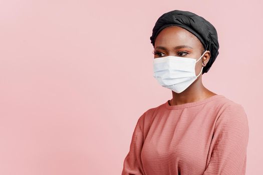 Muslim girl is protected of coronavirus with medical mask close-up. African woman in quarantine period. Social distance. Stay at home.