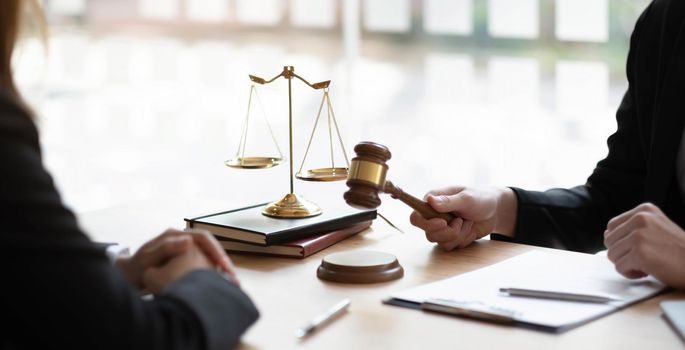 Business and lawyers discussing contract papers with brass scale on desk in office. Law, legal services, advice, justice and law concept picture with film grain effect.