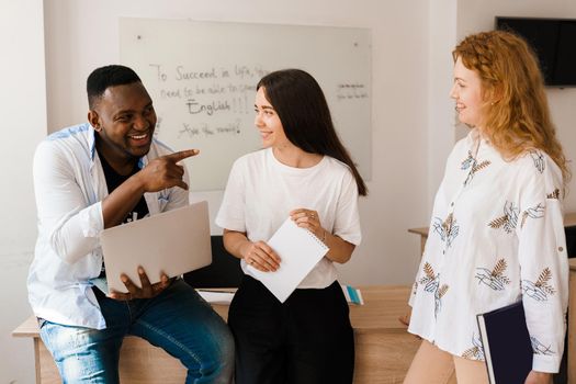 Online multiethnic attractive group of teachers study and laught, discuss something. Remote work in multinational group with laptop.