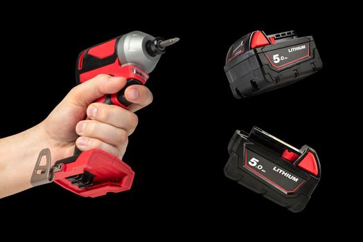 Drill in hand on a black isolated background. Cordless drill or screwdriver in a male hand. Removable lithium battery casts a shadow. The concept of selling and using cordless tools