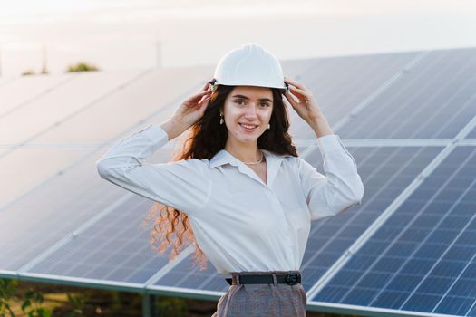 Engineer with solar panels stands in row on the ground at sunset. Green energy. Solar cells power plant business