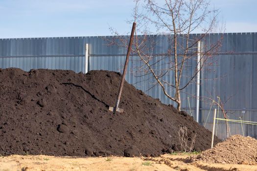 Heap of black soil and a spade in a garden