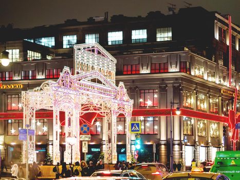 MOSCOW, RUSSIA - December 12, 2019. TSUM store facade decorated for New Year and Christmas celebration. Crowd of people near holiday gates decorated with light bulbs.