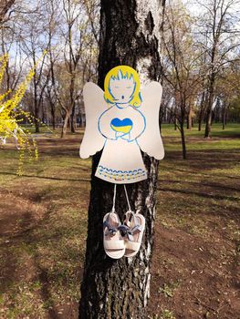 Cardboard angels on a birch trunk in a park in memory of the Ukrainian children who died in the war with Russia.