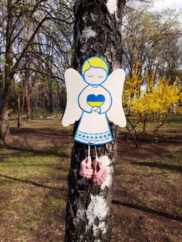 Cardboard angels on a birch trunk in a park in memory of the Ukrainian children who died in the war with Russia.