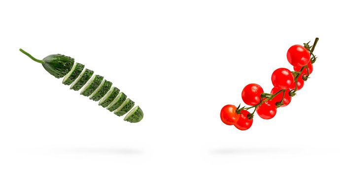 Isolated vegetables. Ingredients for salad. Mixed slices of cucumber and tomato in the air isolated on white background