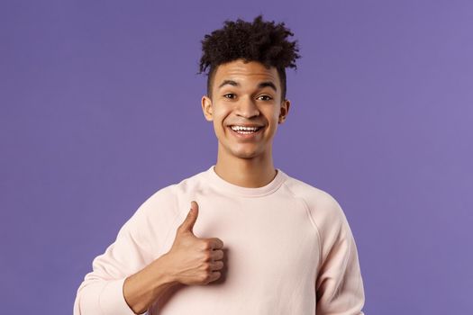 Close-up portrait of satisfied young smiling man recommend something really good, show thumbs-up in approval, like and agree with perfect choice, leave positive feedback, smiling happy.