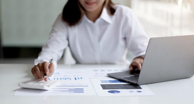 Business woman using calculator for do math finance on wooden desk in office and business working background, tax, accounting, statistics and analytic research concept.