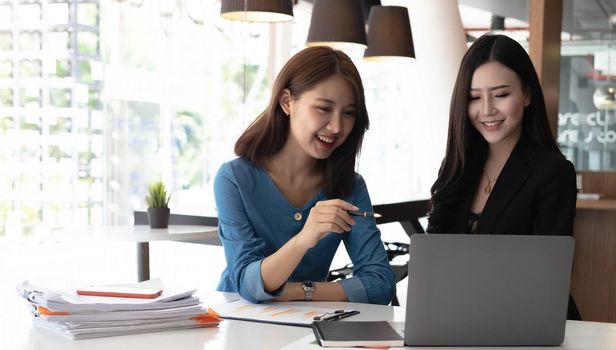 Two asian business woman work together to get the job done at the office..