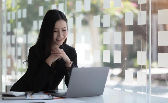 Charming asian businesswoman sitting working on laptop in office..