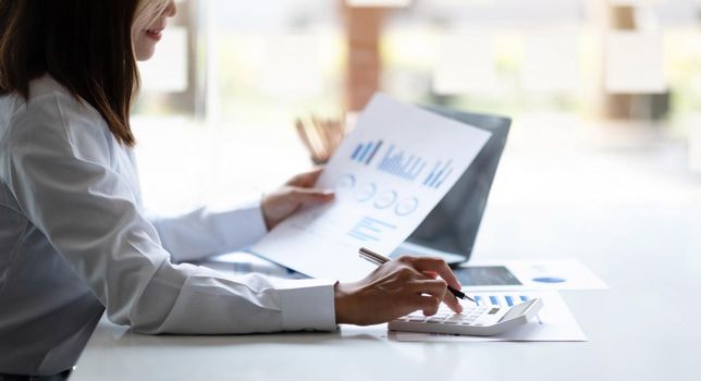 Business woman using calculator for do math finance on wooden desk in office and business working background, tax, accounting, statistics and analytic research concept.