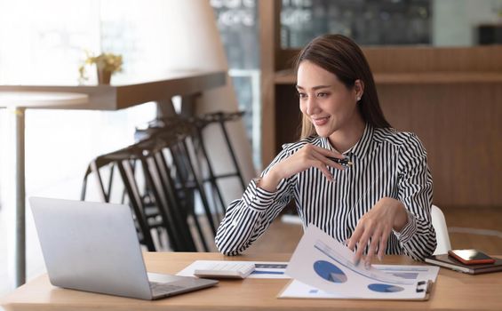 Charming asian businesswoman sitting working on laptop in office..