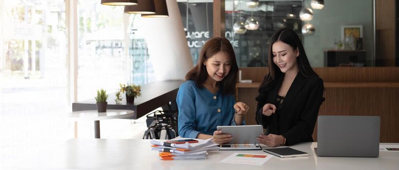 Two asian business woman work together to get the job done at the office..