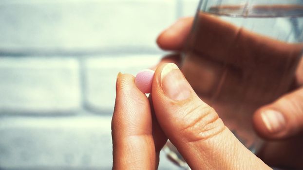 Woman taking medicine with a glass of water