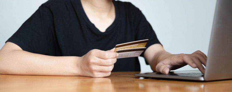 Close up woman hand using credit card and smartphone laptop for buying online shopping.