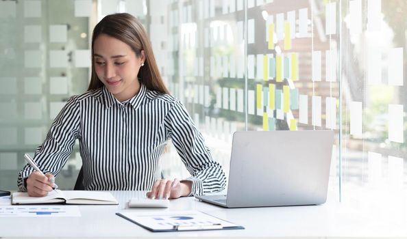 Business woman using calculator for do math finance on wooden desk in office and business working background, tax, accounting, statistics and analytic research concept.