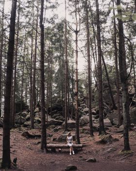 Slavic tanned fair-haired young girl with a boater hat on nature. Traveler tourist in a dark forest. constant tone of clothes. dark brown background