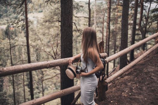 Slavic tanned fair-haired young girl with a boater hat on nature. Traveler tourist in a dark forest. constant tone of clothes. dark brown background