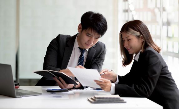 Two asian business woman and businessman work together to get the job done at the office..