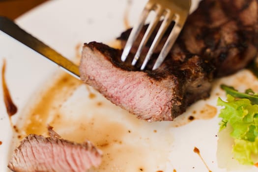 Steak on white plate on the on wooden table. Medium-rare juicy meat.