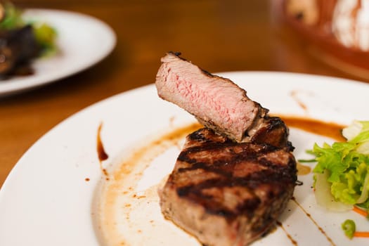 Steak on white plate on the on wooden table. Medium-rare juicy meat.