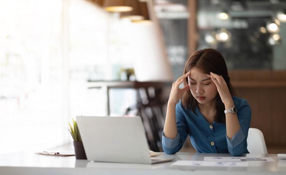 Image Asian woman are stressed, pain in their eyes, work with their laptop, taking notes at office..