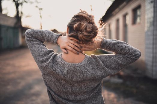 beautiful young blonde model girl smile. gray knitted sweater. On the Sunset. Portrait. hair tied in a bun